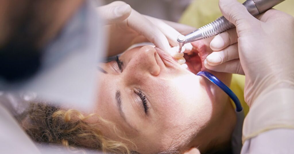 Dental professional cleaning a patient's teeth — choosing the right dental implant specialist