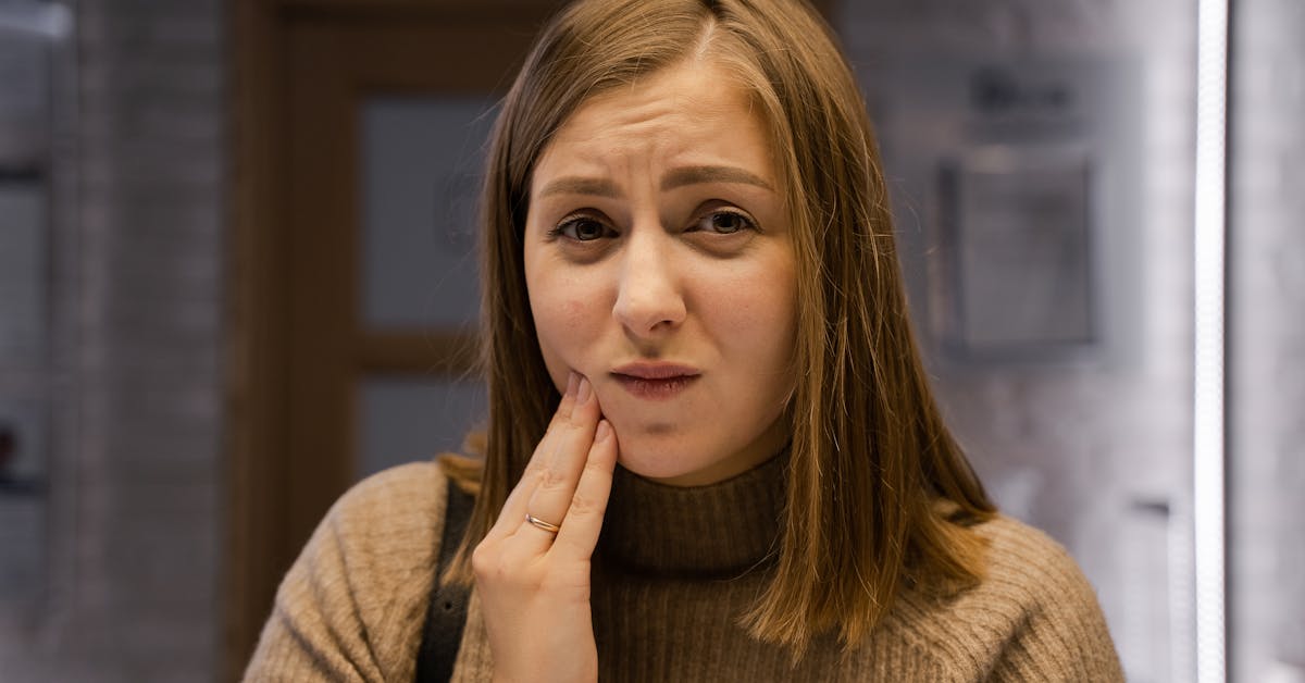 Woman with hand on cheek in tooth pain seeking relief at a dentist