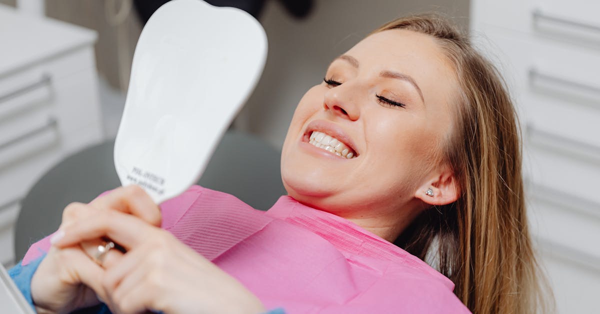 Patient in dental chair smiling into a mirror after broken-tooth care