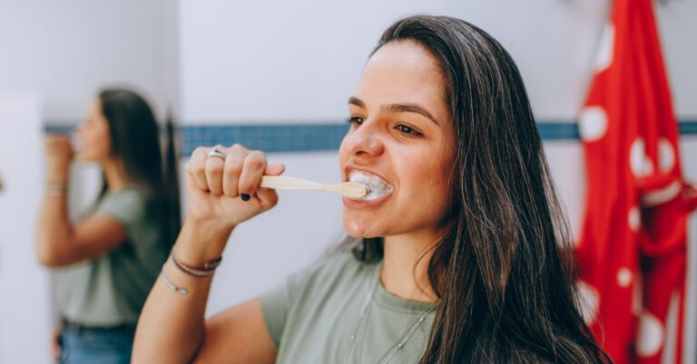 Woman brushing teeth — daily habits to maintain Invisalign aligners