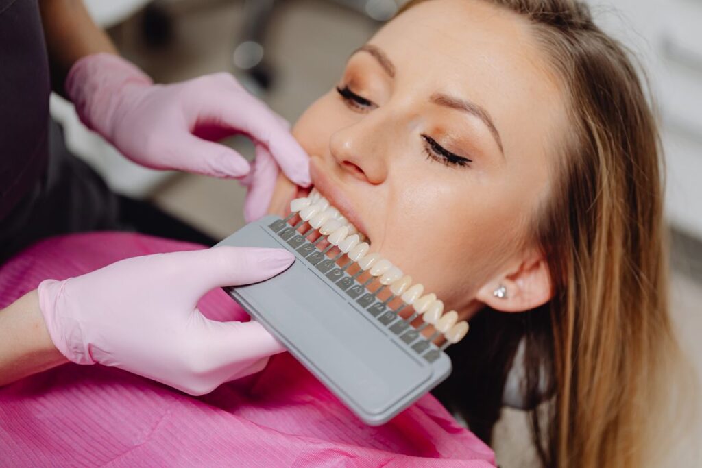 Dentist holding a dental shade guide in front of a patient to assess teeth whitening cost and options in Archway