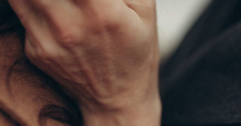 Close-up of a hand resting on a cheek in dental discomfort — when to seek emergency dental care